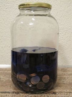 a glass jar filled with coins sitting on top of a wooden table next to a wall