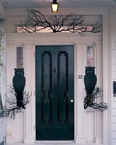 a black front door on a white house with two large vases in the window