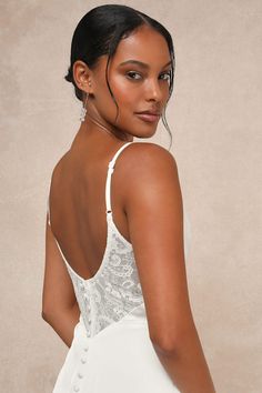 a woman in a white dress with her back turned to the camera and wearing earrings