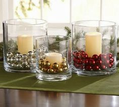 three glass vases with candles and ornaments in them