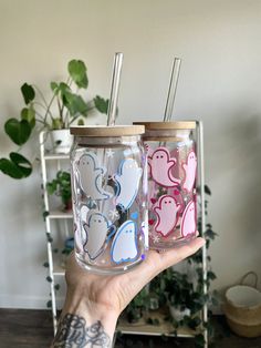 someone holding up two tumblers with stickers on them