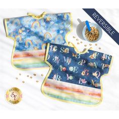 two bibs with rainbows and clouds on them next to a bowl of cereal