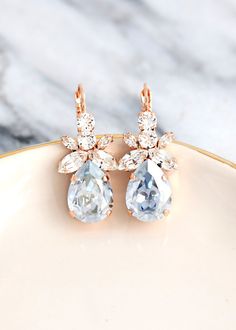 two pairs of gold earrings with blue topazte and white diamonds on a plate