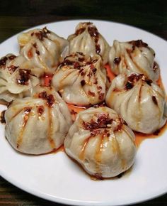 a white plate topped with dumplings covered in sauce