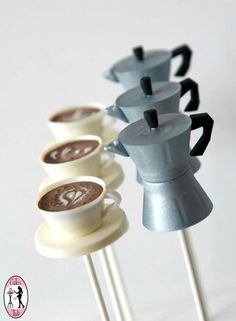 four coffee cups sitting on top of wooden sticks