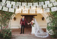 a bride and groom holding hands in front of an archway decorated with paper cutouts