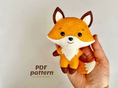 a hand holding a small stuffed animal that looks like a fox