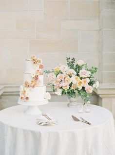 a white table topped with a cake and flowers