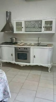 a white kitchen with an oven, microwave and table cloth on the floor in front of it