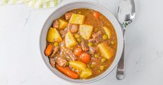 a white bowl filled with stew next to a spoon