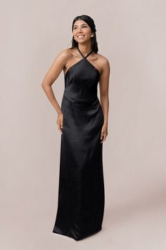 a woman in a long black dress posing for the camera with her hands on her hips