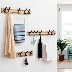 a living room filled with furniture next to a wall mounted coat rack and potted plant