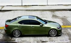 a green car parked in a parking lot next to a yellow line and white wall