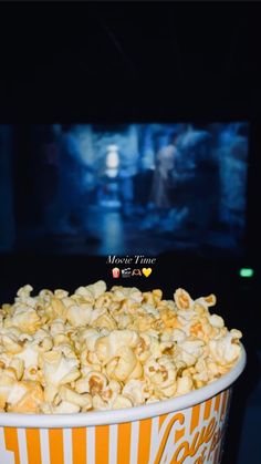 a bowl filled with popcorn sitting on top of a table next to a tv screen