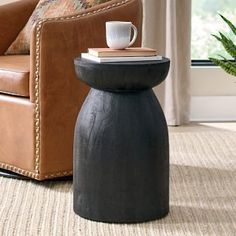 a living room with a chair, table and potted plant on the floor in front of a window