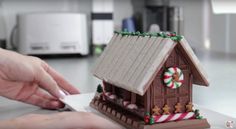 someone is decorating a gingerbread house with candy canes