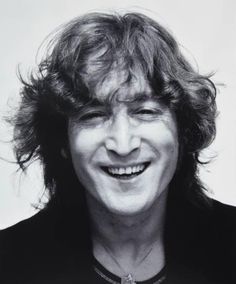 a black and white photo of a man with long hair smiling at the camera,