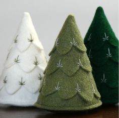 three small christmas trees sitting on top of a wooden table