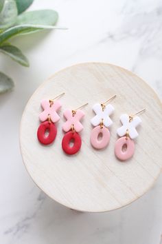 three pairs of pink, white and red earrings sitting on top of a wooden table