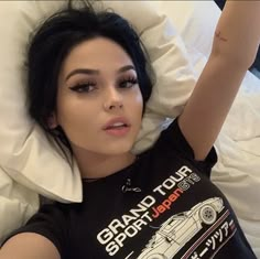 a woman laying in bed wearing a black shirt