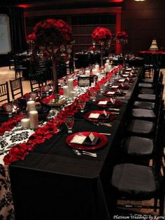 a long table is set with black and red place settings