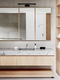 a bathroom with two sinks, mirrors and shelves on the wall next to each other