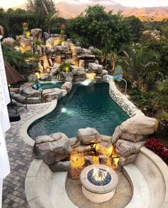 an outdoor swimming pool with waterfall and fire pit