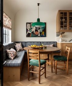 a kitchen table with two chairs and a bench in front of it, next to a painting on the wall