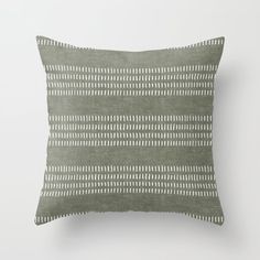 a green and white pillow with an abstract design on the front, sitting against a wall