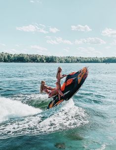 two women riding on the back of a jet ski while being pulled by a boat