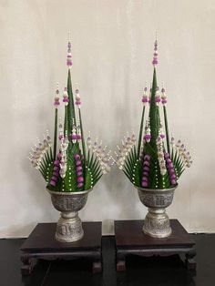 two silver vases with purple and white flowers in them