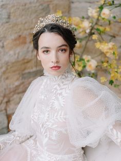 a woman wearing a tiara sitting on a white couch with flowers in the background