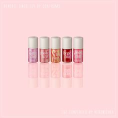 four lip glosses in different colors on a pink background