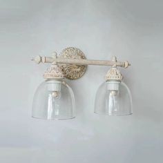 two light bathroom fixture with clear glass shades on the top and bottom, hanging from a white wall