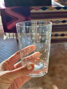 a person holding up a glass with water in it's hand on top of a table