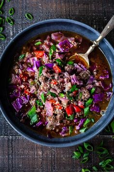 a bowl filled with meat and vegetables on top of a wooden table