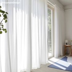 a room with white curtains and a blue rug on the floor next to a window