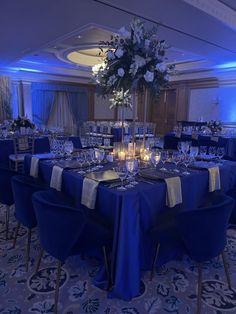 a table set up with blue linens and candles for a formal dinner or party