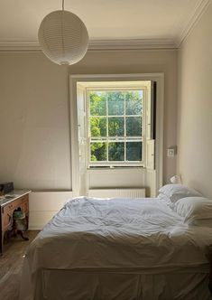 a bed sitting under a window in a bedroom