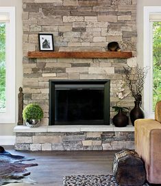 a living room with a stone fireplace in the center and two vases on the mantle