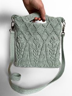 a hand holding a green knitted purse