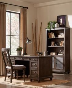 an office desk with two chairs and a bookcase in front of a large window