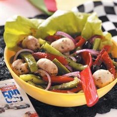 a yellow bowl filled with vegetables on top of a table