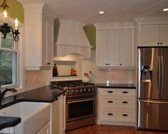 a kitchen with white cabinets and black counter tops, stainless steel appliances and an island