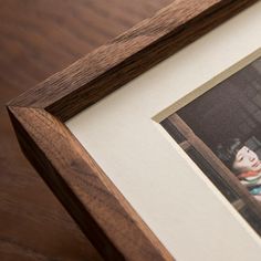 an old photo is hanging on the wall next to a wooden frame with a woman's face in it