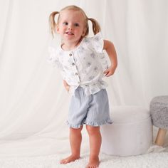 Get ready for some summer fun with the Aliya Skye Short and Top set! These super soft cotton shorts feature an elastic waist for ultimate comfort, while the top boasts flutter sleeves and buttons down the front. Perfect for any little girl, this outfit is sure to become her go-to choice. Wash cold with like colors Lay flat to dry; Minor shrinkage likely if tumble dried 100% cotton Playful Short Tops For Spring, Cute Short Tops For Playtime, Summer Playtime Ruffle Bloomers, Spring Playwear Short Set, Spring Short Set For Playwear, Ruffled Bottoms For Summer Playtime, Spring Playwear Short-sleeved Tops, Summer Playwear Tops With Elastic Waistband, Short Cotton Tops With Ruffles