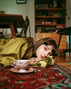 a woman laying on the floor next to a tea cup