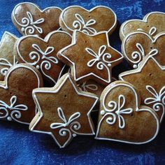 some cookies that are shaped like hearts and stars on a blue table cloth with white icing