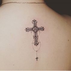 a cross tattoo on the back of a woman's upper arm and lower shoulder