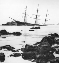 an old photo of a ship in the ocean with rocks and seaweed around it